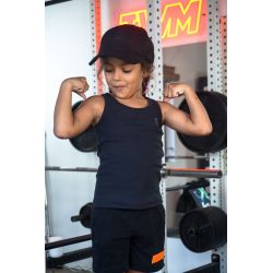 Jeune fille brunette en débardeur noir et casquette noire, flexion des bras montrant ses muscles dans une salle de sport avec un