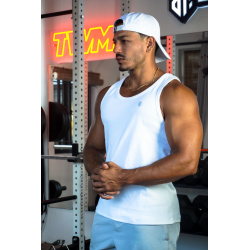 Homme musclé portant débardeur blanc ESSENTIAL, casquette arrière, chaîne dorée, en salle de sport avec poids et équipements au