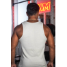 Homme vu de dos portant un débardeur beige, musculature saillante, chaîne dorée au cou, en salle de sport avec éclairage rouge.