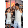 Joueur adulte et enfant en débardeurs beige, se faisant face et montrant des muscles dans une salle de sport.