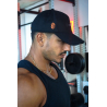 Casquette noire en coton avec attache orange portée par un homme au gym, vue de profil.