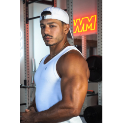 Casquette blanche en coton portée à l’envers par un homme musclé en débardeur blanc dans une salle de sport.