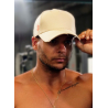 Casquette créme en coton avec attache orange portée par un homme nu-torse, lisant légèrement la visière.