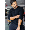Homme musclé en t-shirt noir à manches longues, regard sur le bras, intérieur de salle de sport. Logo “BODYTIME” sur chest.