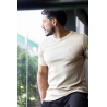 Homme élégant portant un t-shirt beige ESSENTIAL près du corps, vue de profil, intègre logo discret sur la poitrine.