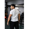 Homme musclé vu de dos dans une salle de sport, porte T-shirt blanc ESSENTIAL, cheveux courts, pantalon noir, en train de se dét